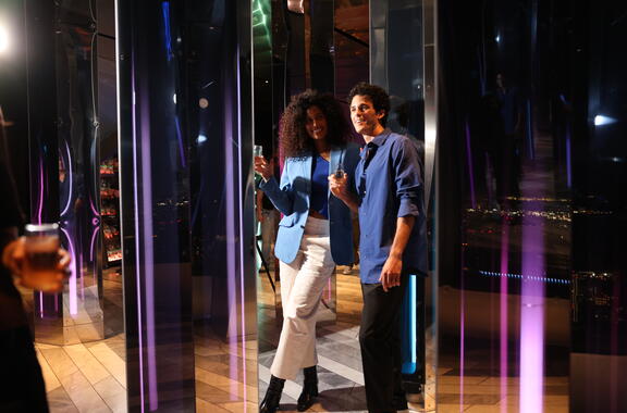 two people walking through pillars of mirrors