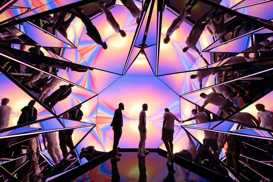 three people standing in front of Kaleidoscope with susnset colors and shapes behind them