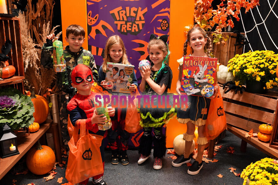 kids in costumes holding Halloween-themed games and toys
