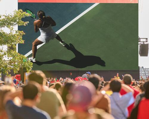 crowd watching a tennis match on a large big screen