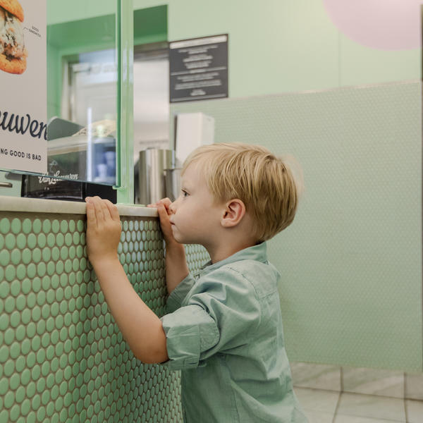 Boy standing in front of an ice cream counter 