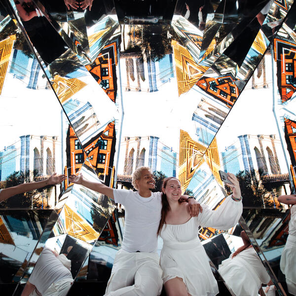 couple in front of a Kaleidoscope showing images of NYC