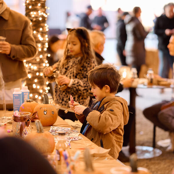 two young kids painting pumpkins at a table 